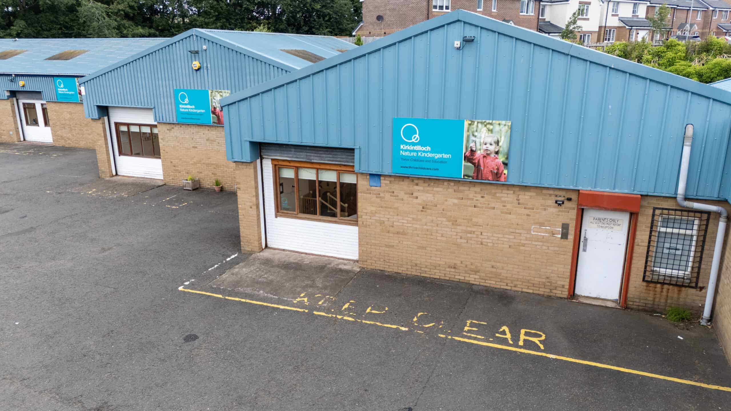 Bright blue-roofed childcare centre exterior at Kirkintilloch with signage for Thrive Childcare, providing early years education and family support in a safe, welcoming environment.