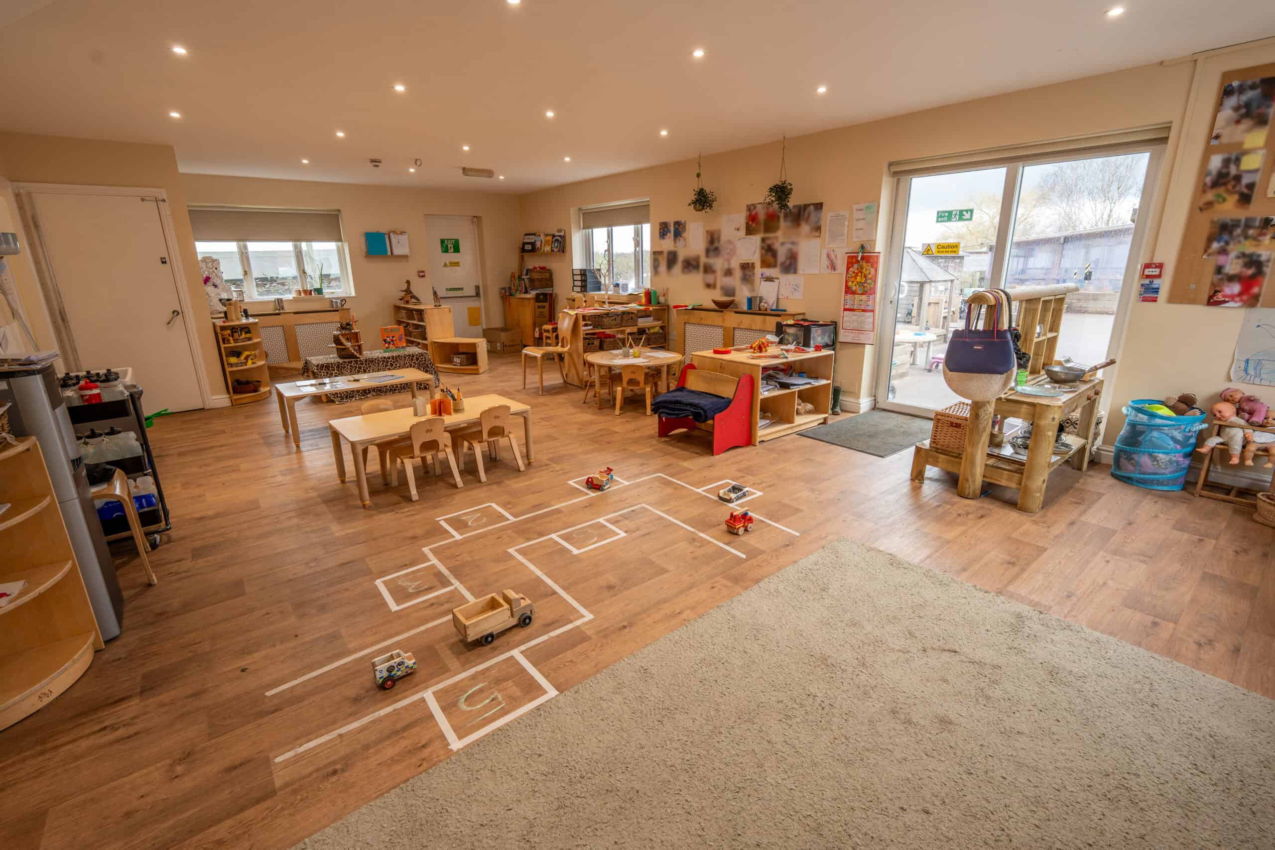 Spacious childcare room with toys, play zones, and learning stations for young children.